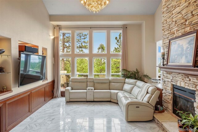 living room featuring a stone fireplace, an inviting chandelier, and a high ceiling