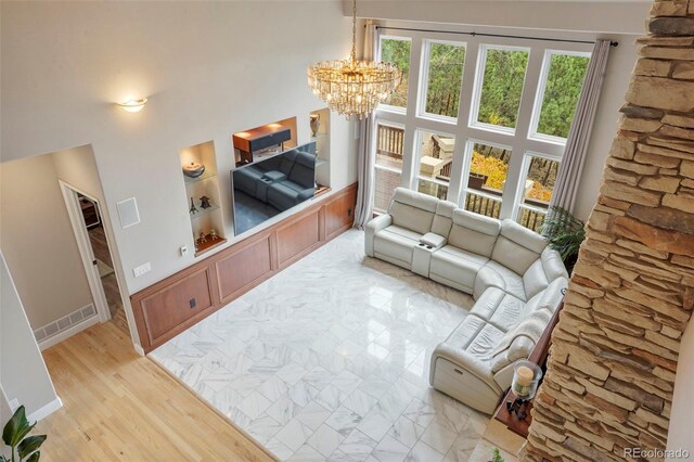 living room with built in features, an inviting chandelier, and light wood-type flooring