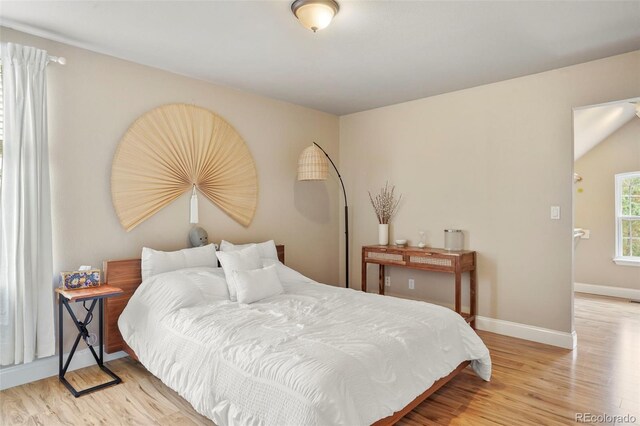 bedroom with light hardwood / wood-style flooring and lofted ceiling