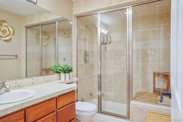 bathroom with vanity, toilet, and a shower with door