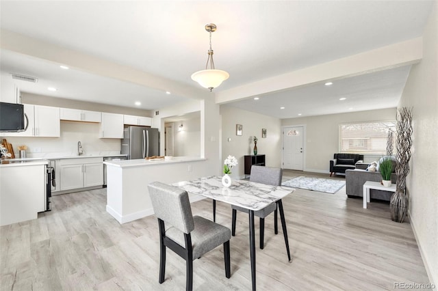 dining space with sink, beamed ceiling, and light hardwood / wood-style floors