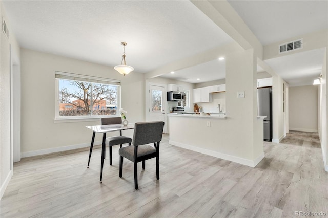 dining space with light hardwood / wood-style floors and sink