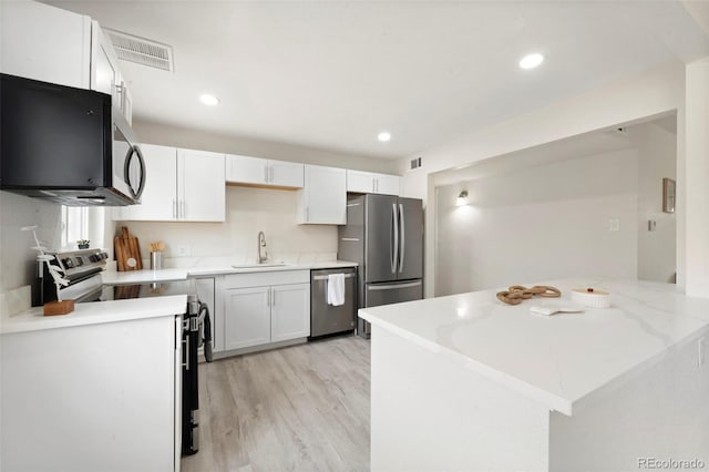 kitchen featuring light wood-type flooring, stainless steel appliances, white cabinetry, and sink