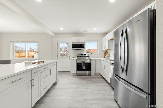 kitchen featuring decorative backsplash, white cabinetry, light hardwood / wood-style flooring, and appliances with stainless steel finishes