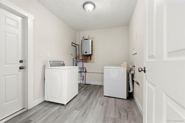 laundry room with a textured ceiling, light wood-type flooring, tankless water heater, and washing machine and dryer