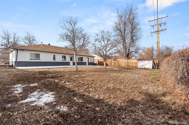 rear view of property featuring a storage unit