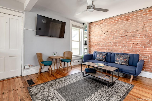 living room featuring ceiling fan, brick wall, and hardwood / wood-style flooring