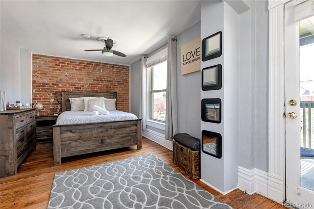 bedroom featuring light hardwood / wood-style floors, ceiling fan, and brick wall