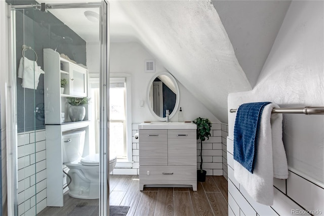 bathroom with vaulted ceiling, vanity, hardwood / wood-style floors, and toilet