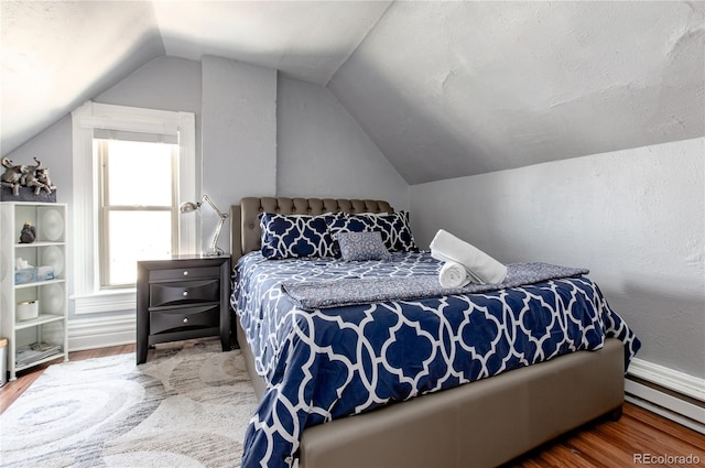 bedroom with wood-type flooring, a baseboard radiator, and lofted ceiling