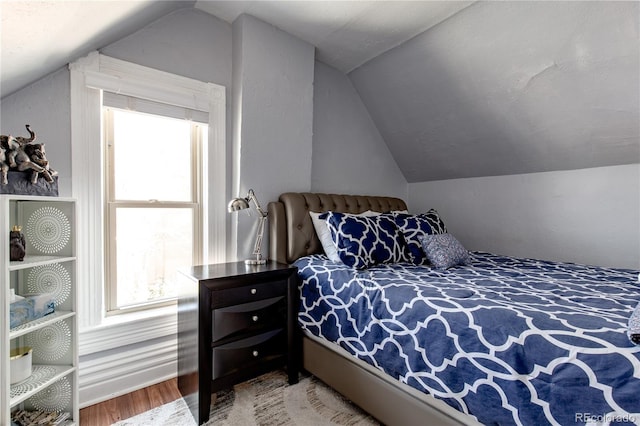 bedroom with wood-type flooring and vaulted ceiling