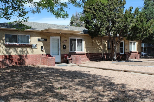 view of front of home with brick siding and roof with shingles