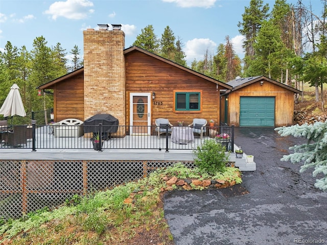 exterior space featuring a garage, an outdoor structure, and a deck