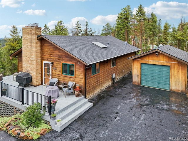 back of property featuring an outbuilding, a garage, and a deck