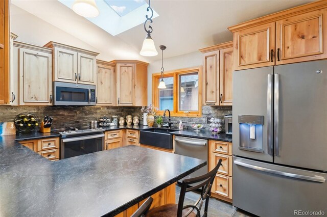 kitchen with sink, backsplash, lofted ceiling with skylight, stainless steel appliances, and decorative light fixtures