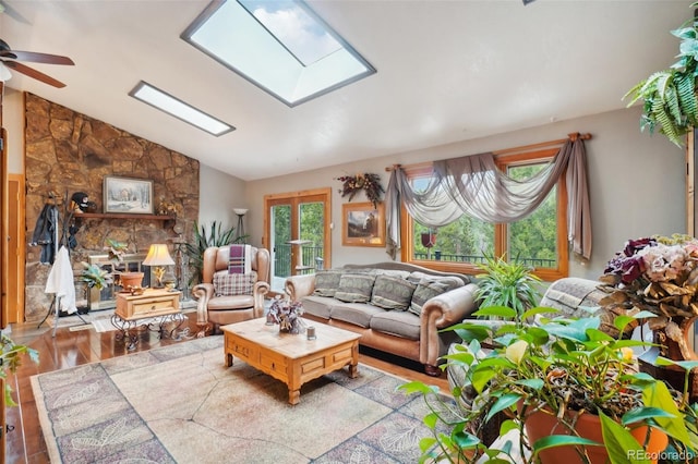 living room featuring ceiling fan, vaulted ceiling with skylight, and light wood-type flooring