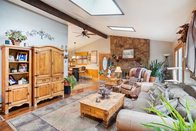 living room with a fireplace, a baseboard radiator, wooden walls, vaulted ceiling with skylight, and light hardwood / wood-style floors