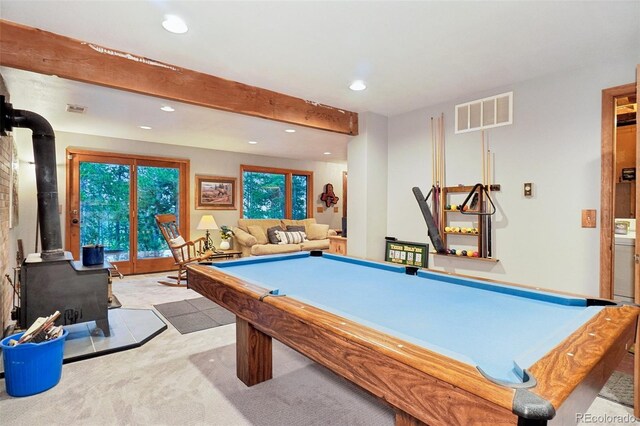 rec room with light colored carpet, beam ceiling, billiards, and a wood stove