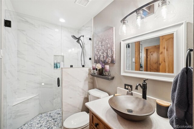 bathroom with a shower with door, vanity, and toilet