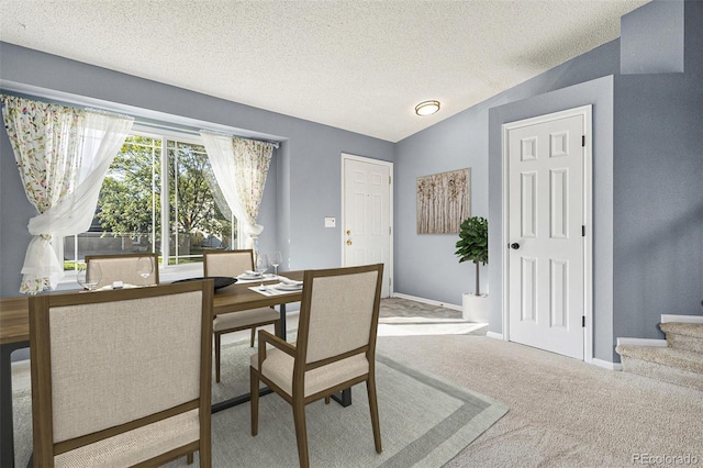 dining space featuring lofted ceiling, a textured ceiling, and light carpet