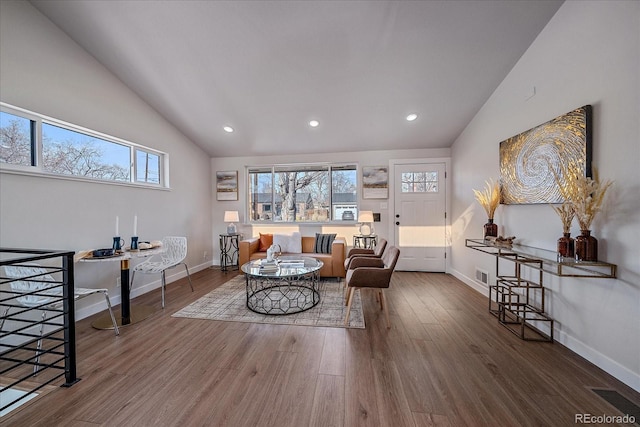 living room featuring wood-type flooring, lofted ceiling, and a healthy amount of sunlight