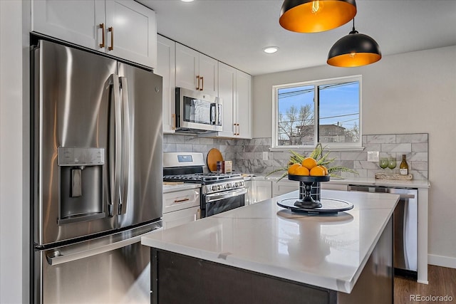 kitchen featuring white cabinets, decorative light fixtures, backsplash, stainless steel appliances, and light stone counters