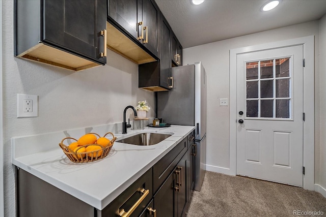 kitchen with sink, light colored carpet, light stone countertops, and stainless steel fridge