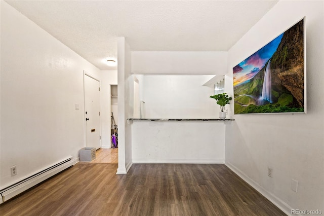 empty room featuring a textured ceiling, dark wood-type flooring, and a baseboard heating unit