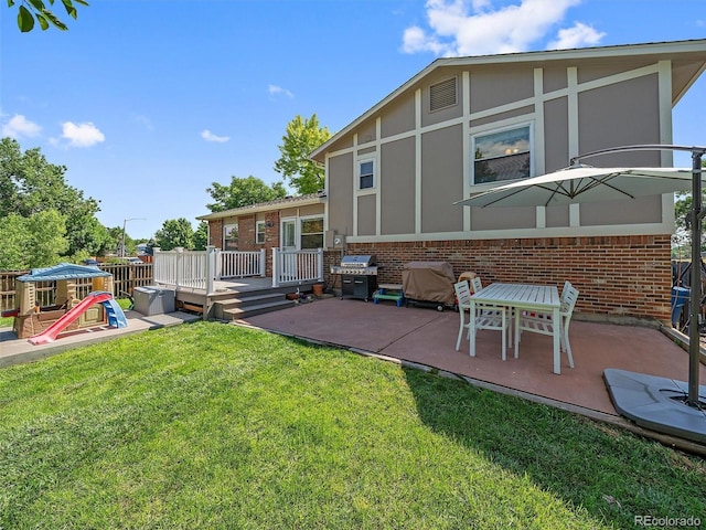 11399 Kendall St, Westminster, CO 80020 - rear view of property featuring brick siding, a patio, a playground, a lawn, and a deck