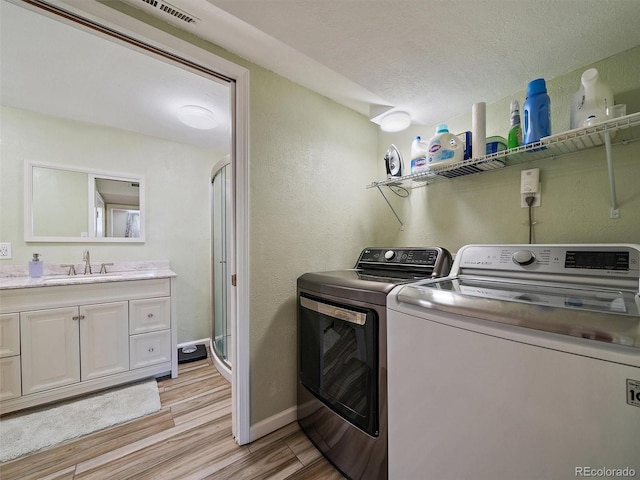 11399 Kendall St, Westminster, CO 80020 - laundry room with separate washer and dryer, light wood-style floors, a textured wall, and a textured ceiling