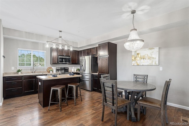 15800 E 121st Ave Unit 3, Brighton, CO 80603 - kitchen featuring appliances with stainless steel finishes, dark brown cabinets, a kitchen island, light countertops, and a kitchen bar
