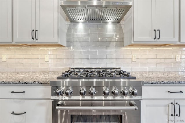 kitchen with white cabinets, light stone countertops, wall chimney range hood, and stainless steel range