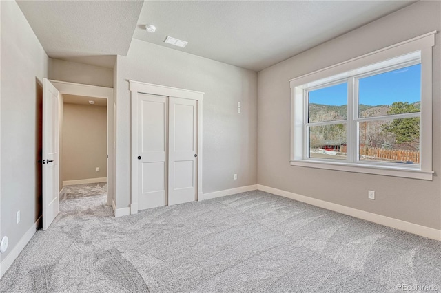 unfurnished bedroom with a closet, light carpet, and a textured ceiling