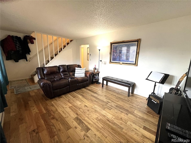 living area featuring stairway, light wood finished floors, and a textured ceiling