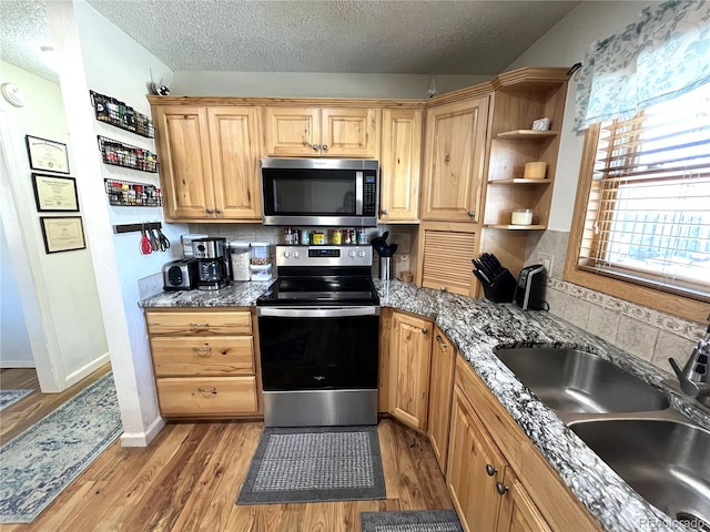 kitchen featuring decorative backsplash, light wood-style flooring, appliances with stainless steel finishes, open shelves, and a sink