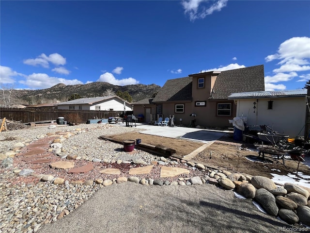 back of property with stucco siding, a patio area, a mountain view, and fence