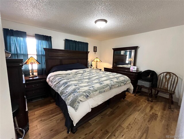 bedroom with a textured ceiling and wood finished floors