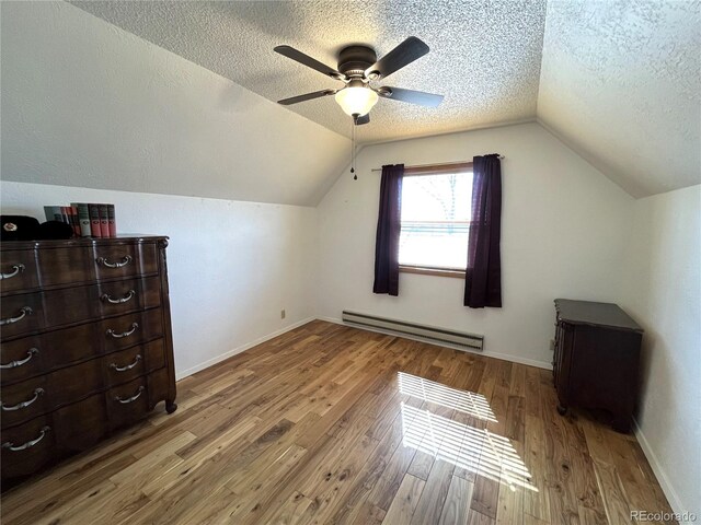 bonus room featuring a textured ceiling, lofted ceiling, wood finished floors, baseboards, and baseboard heating