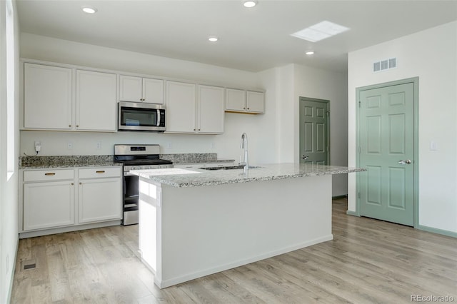 kitchen with light wood-style flooring, white cabinets, stainless steel appliances, and a sink