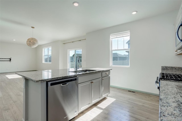 kitchen with visible vents, light stone countertops, light wood-style flooring, appliances with stainless steel finishes, and a sink