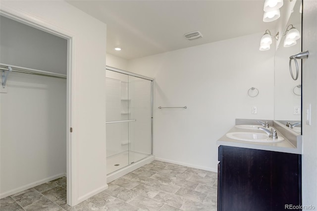 bathroom featuring visible vents, a stall shower, a sink, double vanity, and baseboards