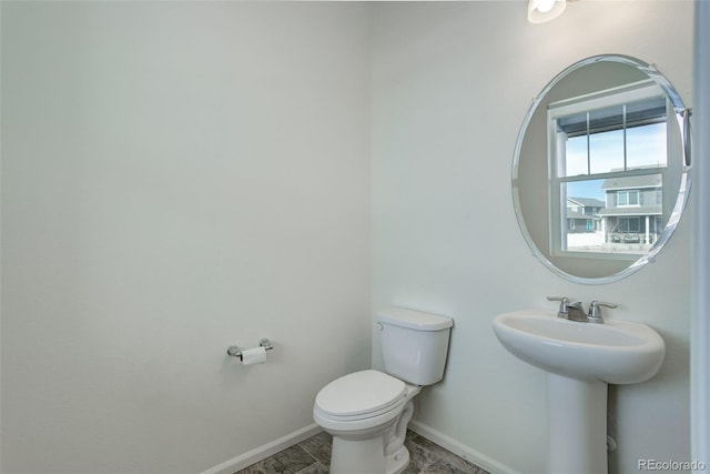 bathroom featuring toilet, baseboards, and a sink