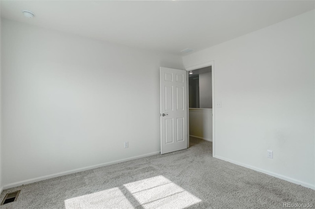 carpeted spare room with visible vents and baseboards