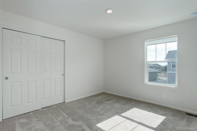 unfurnished bedroom with a closet, visible vents, baseboards, and carpet floors