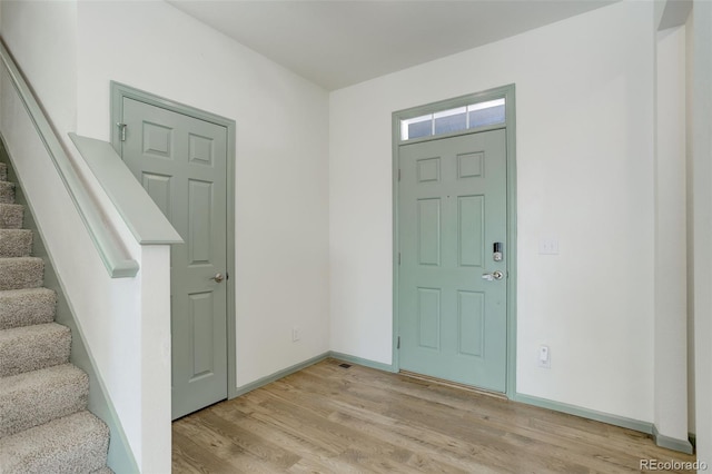 entrance foyer featuring stairway, baseboards, and light wood finished floors