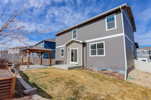 rear view of property featuring a gazebo, a patio area, fence, and a lawn