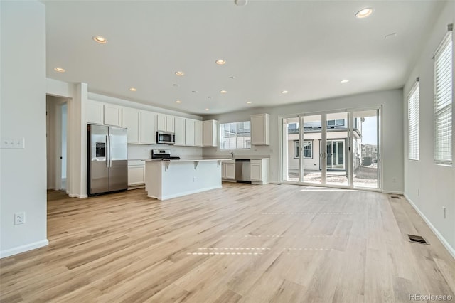 kitchen with recessed lighting, stainless steel appliances, white cabinets, and light wood-style flooring