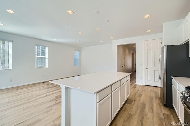 kitchen featuring recessed lighting, a kitchen island, light wood-type flooring, and light countertops