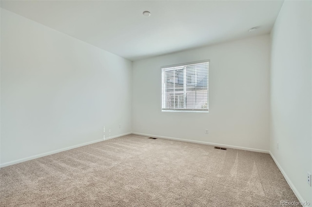 carpeted empty room with visible vents and baseboards