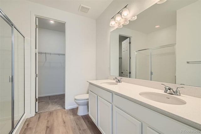 bathroom with wood finished floors, visible vents, a stall shower, and a sink